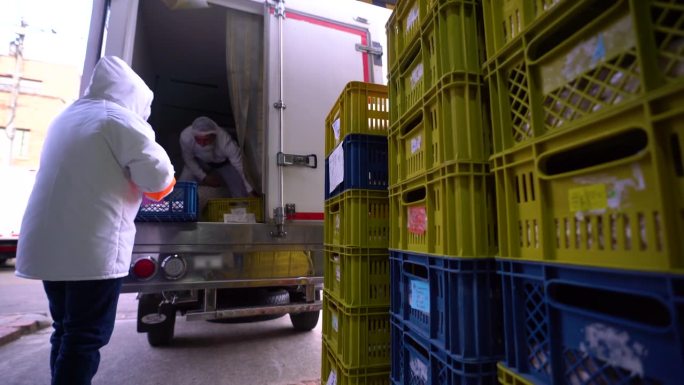 在一家食品加工厂，一组员工将一篮篮的食品装进冷藏车