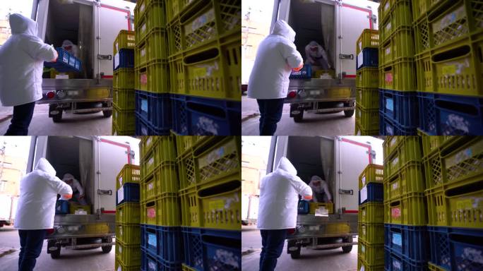 在一家食品加工厂，一组员工将一篮篮的食品装进冷藏车