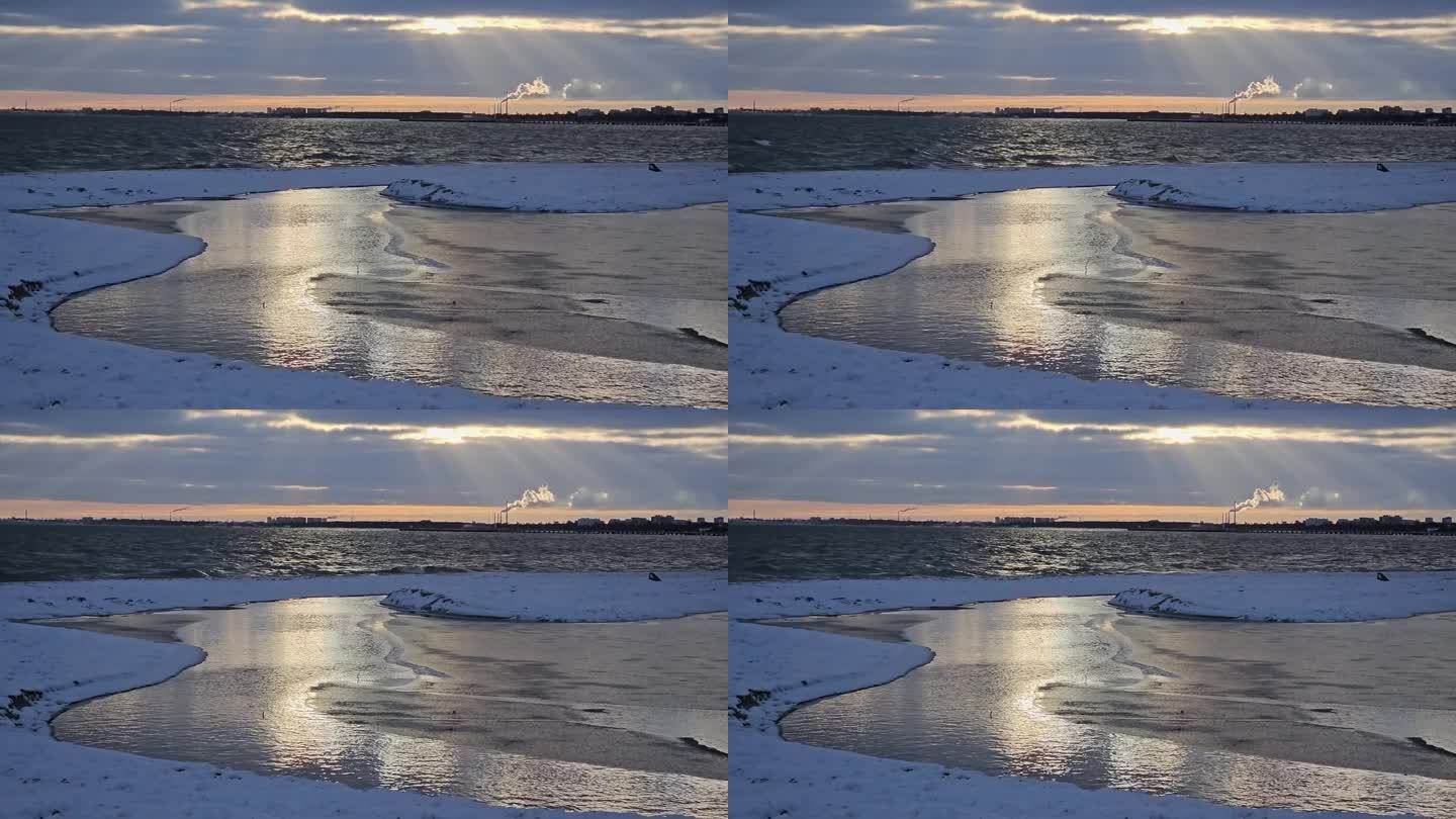 波兰格但斯克海湾上太阳升起的彩色海面反射。地平线上冒着烟的烟囱。光线散布在整个场景中。