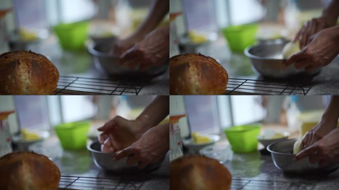 聚焦架从熟面包卷到在钢碗中手揉生面团，拍摄为近距离慢镜头