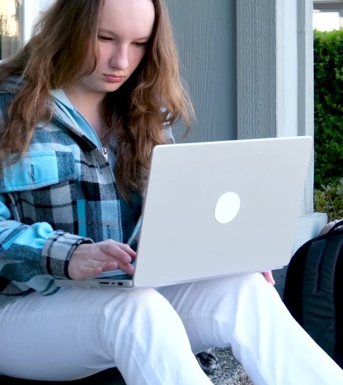 打开笔记本电脑开始工作从学校回家忘记钥匙穿着外套长发的女人坐在楼梯上使用笔记本电脑白天在城市远程项目