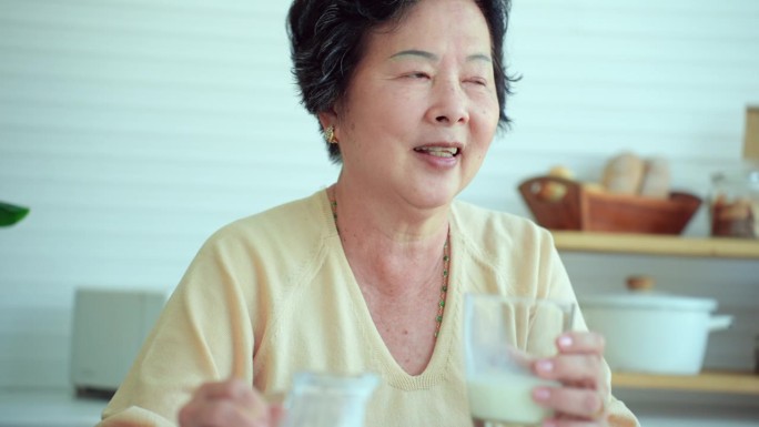 有吸引力的亚洲老年人早上在家喝一杯牛奶，以获得钙、磷、B族维生素等重要营养物质，有利于身体健康。老妇