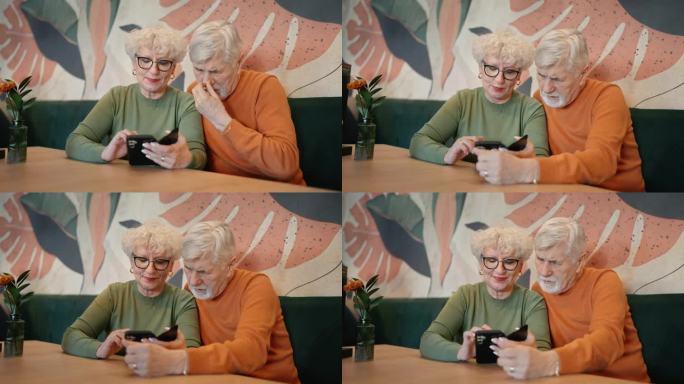 穿着便服的老夫妇在餐厅的餐桌上边玩手机边聊天