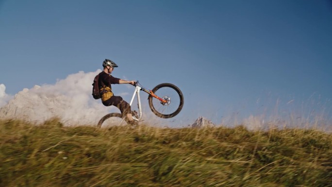 男子山地自行车手在草地上用自行车表演轮滑的镜头