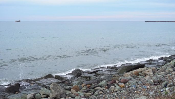 海浪拍打着岩石海岸，溅起水花，在地平线上翻船。平静和宁静，冥想和放松，自然美景的屏幕保护程序。岩石海