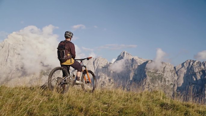 SLO MO无人机拍摄的男性骑自行车的人坐在自行车对落基山脉在阳光明媚的一天