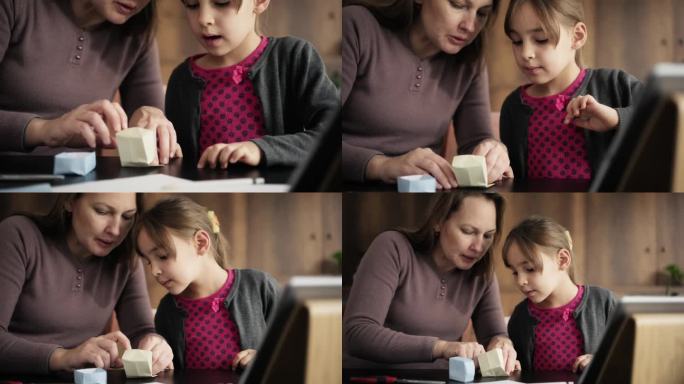 儿童女孩和母亲做折纸玩具使用彩色纸的步骤，按照指示的视频教程在数字平板电脑上