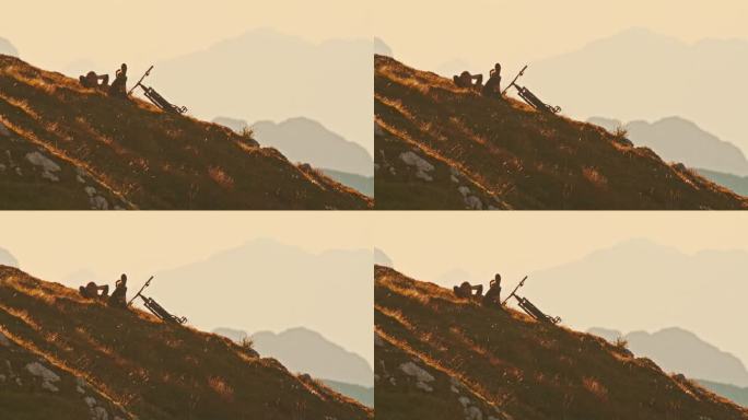 SLO MO锁定镜头，放松的男性山地自行车手躺在草坡上，面对天空和雾山