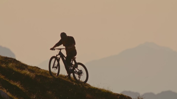 SLO MO男性山地自行车手准备骑自行车在山上对晴朗的天空在日落