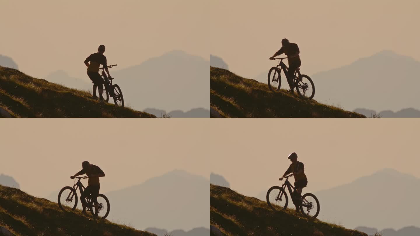 SLO MO男性山地自行车手准备骑自行车在山上对晴朗的天空在日落