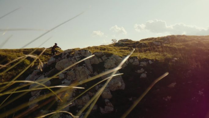 SLO MO手持拍摄的男子自行车表演特技与自行车在落基山对天空在阳光明媚的一天