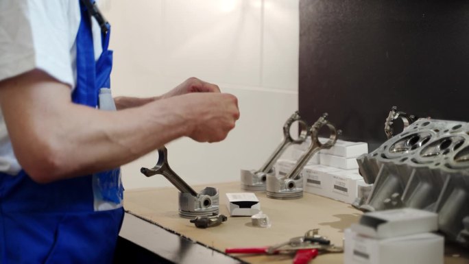 专业机械师组装发动机组件，在工作台上为汽车大修安排活塞、环、衬套。在车库车间由技术人员进行精密装配。