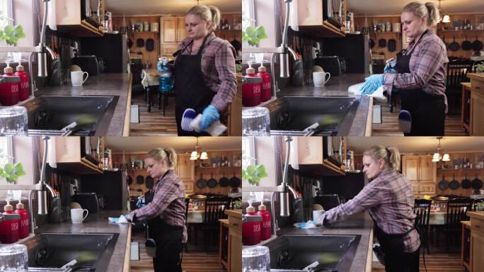 戴着防护手套的女看门人正在擦拭厨房柜台。家政保洁服务职业。手持摄像机运动