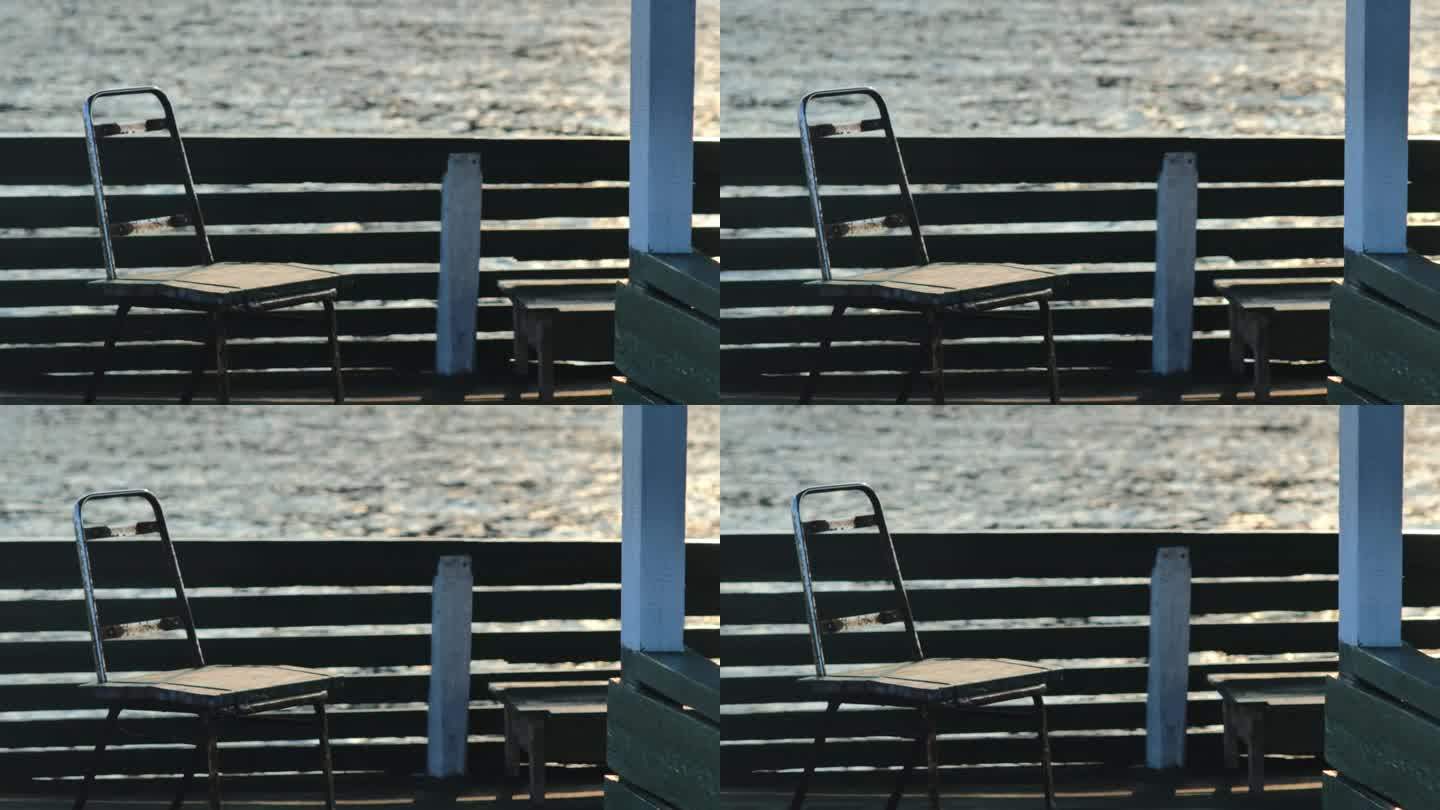 下午，在平静的大海的背景下，漂浮在房子边上的一把生锈的旧铁木椅子