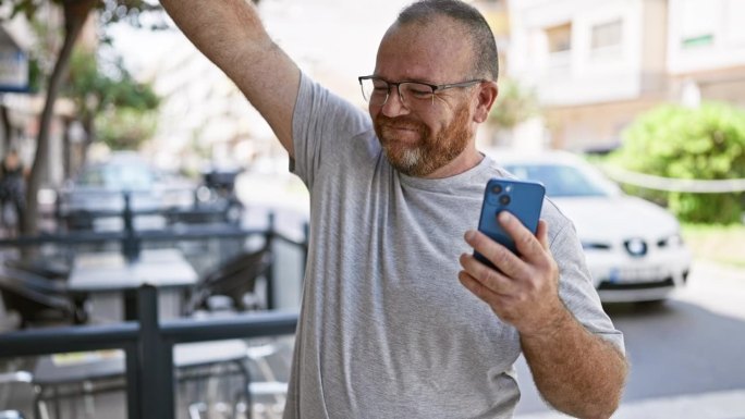 尤里卡!开朗的白种胡子中年男子，首次在城市户外街道上用智能手机庆祝，并发了一条获胜短信!