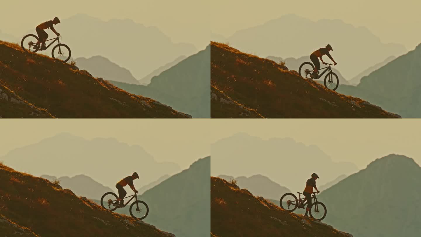 男子运动员在日落时骑山地车下坡时对雾山的侧视图