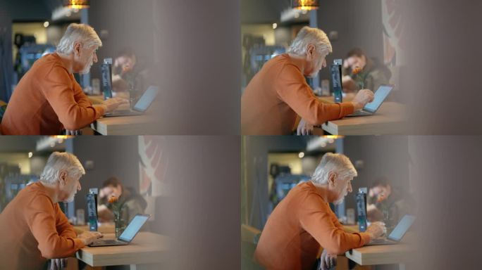 穿便服的老人在餐厅餐桌上使用笔记本电脑的侧视图