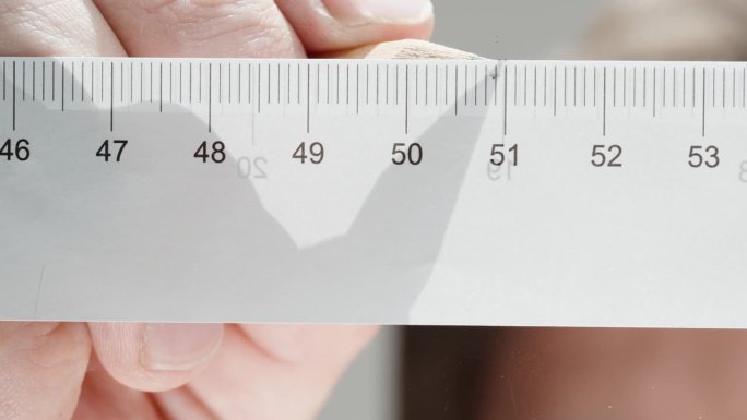 测量尺寸，特写一个人用铅笔做记号。厘米尺。低角度视角聚焦于玻璃