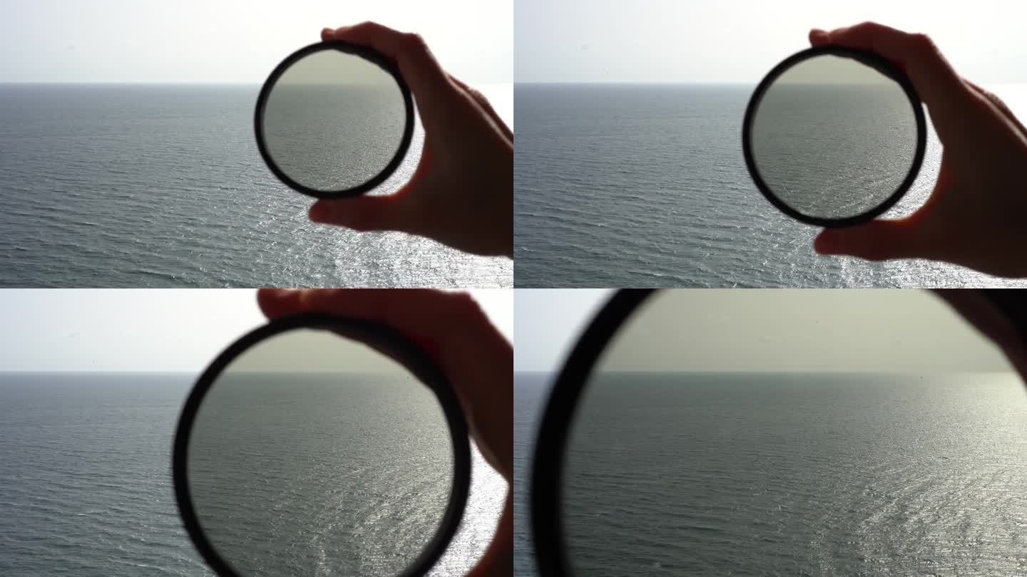 一位女士的手将偏光滤光片放在相机上，拍摄白天阳光照射下的海浪。光学镜头和相机效果的概念