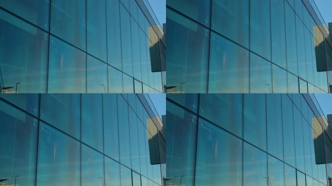 蓝天映照在一座现代建筑外墙的大玻璃板上。