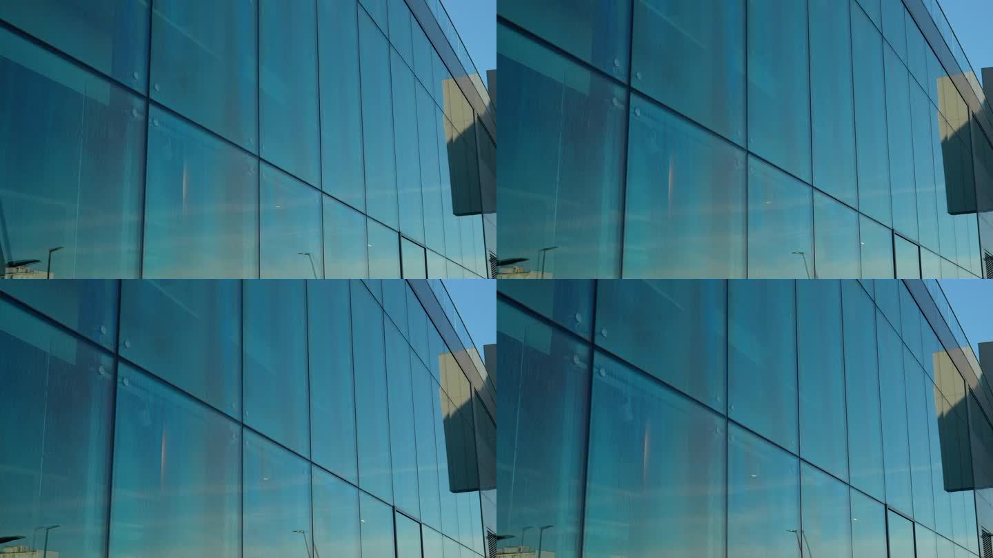蓝天映照在一座现代建筑外墙的大玻璃板上。