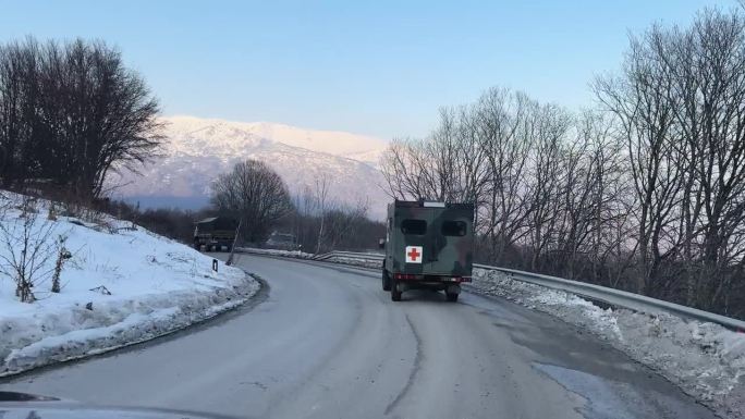 冬季，军医救护车行驶在森林中的乡村山路上