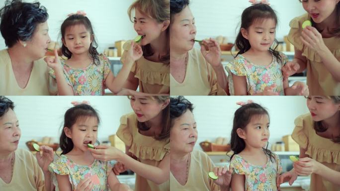 多代亚洲家庭，美丽的其他，老祖母教导和激励年轻的小女孩吃新鲜的黄瓜，这是一种营养丰富的水果，有益健康