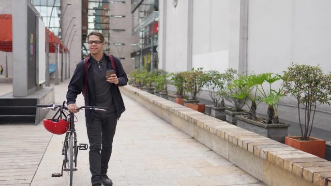 一个年轻人在城市里拿着一个纸咖啡杯，同时扛着自行车