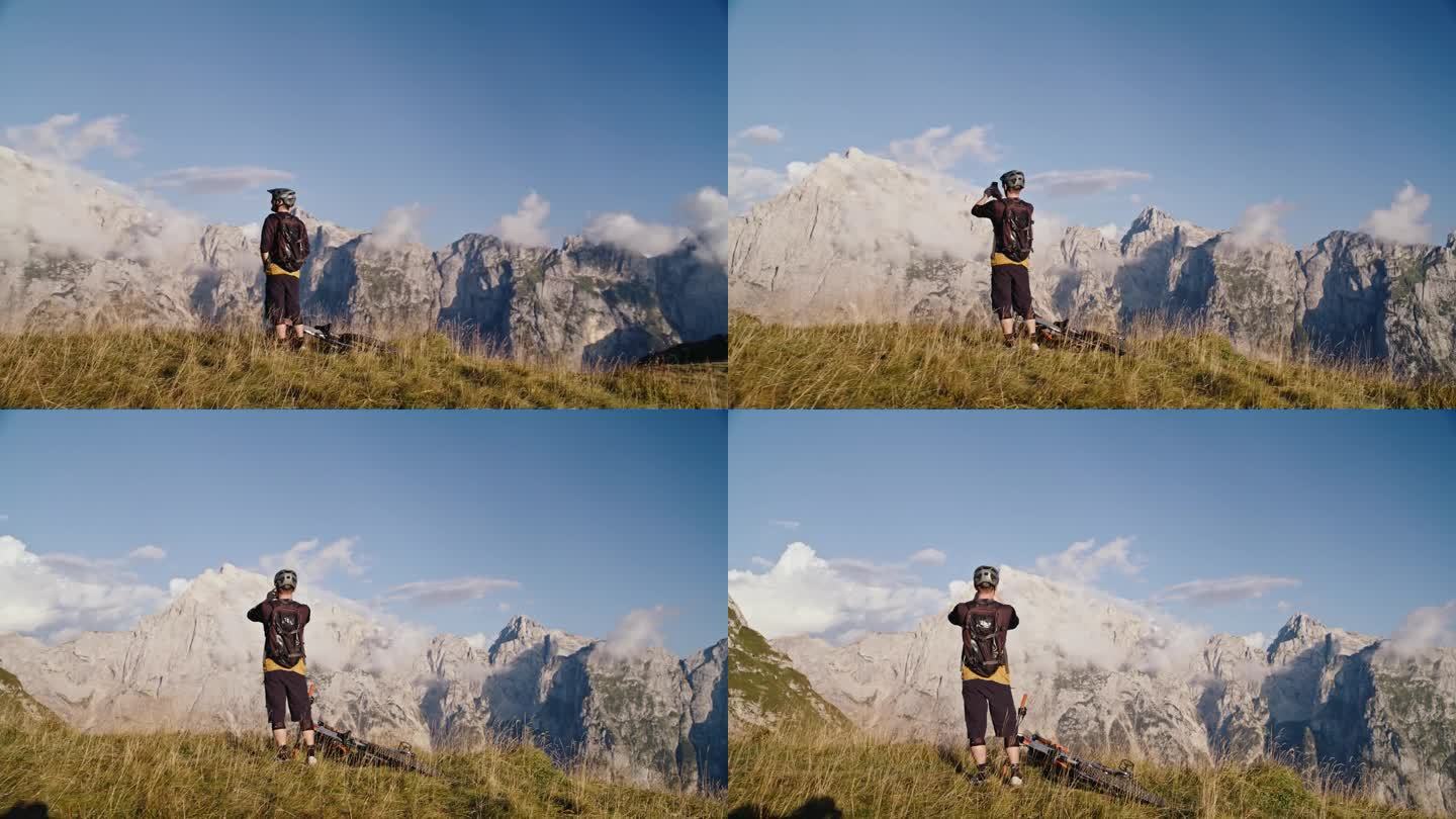 SLO MO无人机拍摄骑自行车的人通过智能手机拍摄落基山脉，而站在球场在阳光明媚的一天