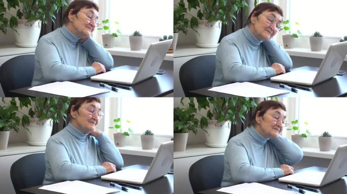 一位上了年纪的妇女在家里用电脑工作，她的脖子很僵硬，正在伸伸脖子