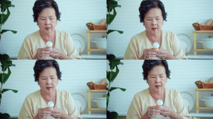 生活在温暖的家庭里，年老的亚洲祖母拿着小药瓶，里面装着治疗或预防阿尔茨海默病的日常药物胶囊。个人观点