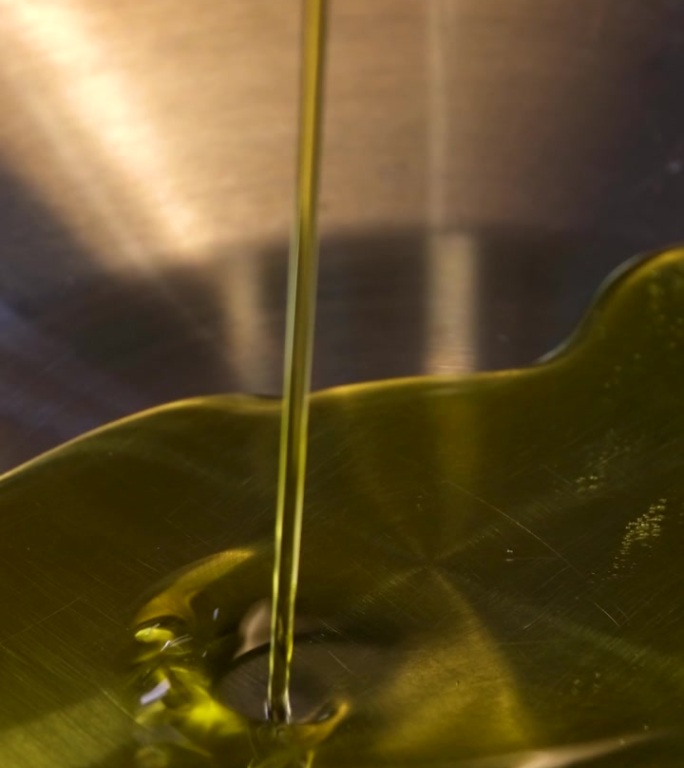 往锅里倒橄榄油，白色背景慢动作给新铸铁炊具调味往煎锅里倒油。高品质4k画面
