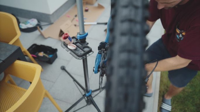 男子在院子里修理山地车踏板的SLO高角度手持镜头。自行车修理。