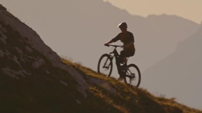 在阳光明媚的日子里，坚定的男性骑自行车者在落基山上移动的SLO手持镜头