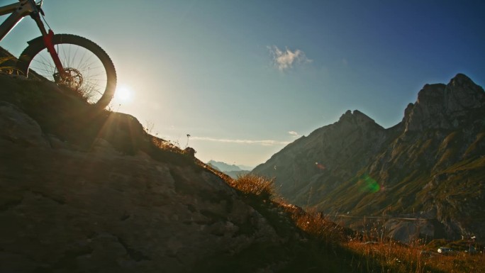 慢动作男子骑自行车在草山对落基山脉和蓝天在阳光明媚的一天