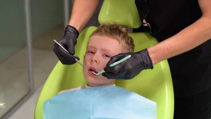 悲伤的小男孩在牙医治疗牙齿时张大了嘴巴