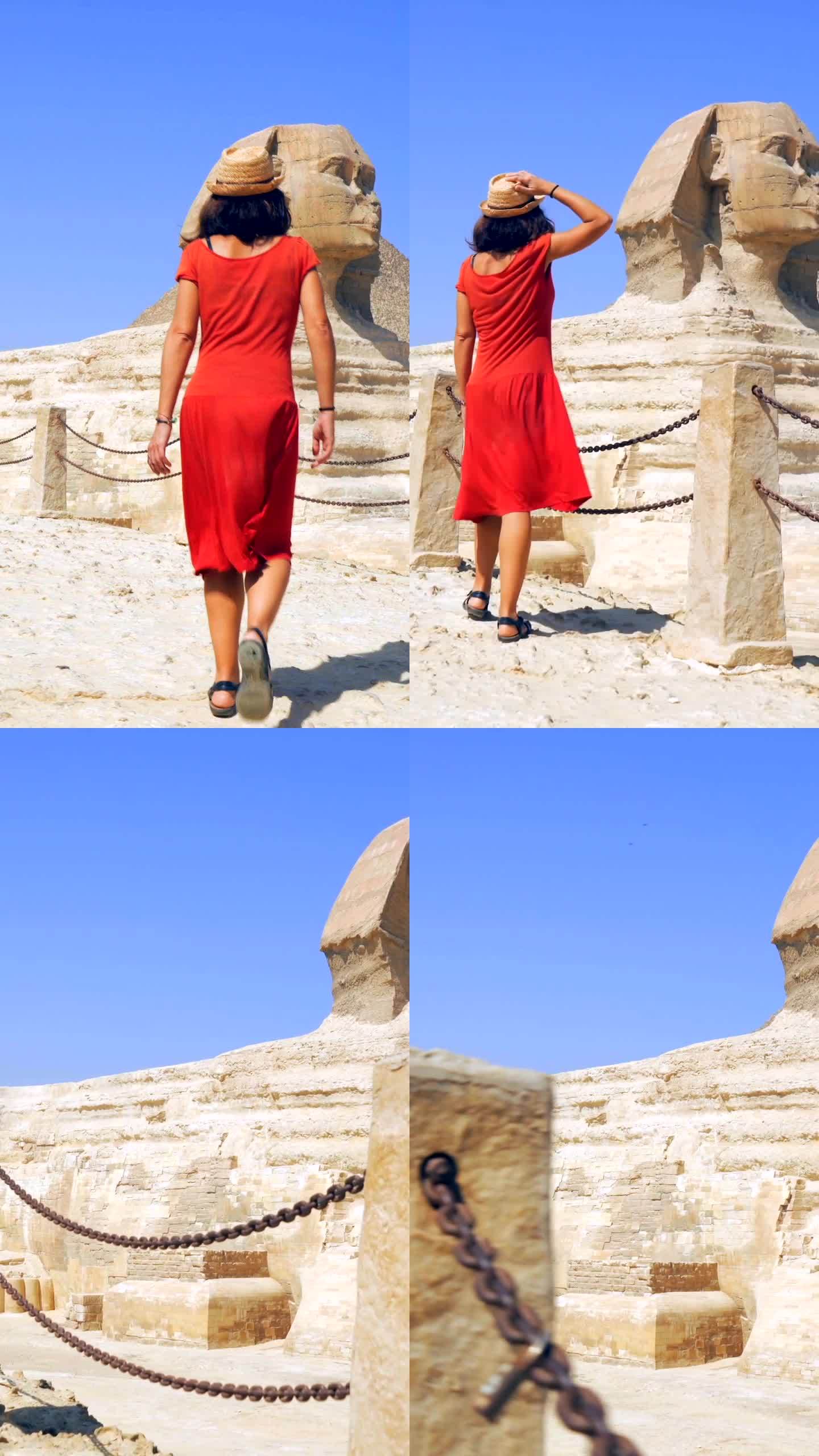 一位身穿红色连衣裙、头戴草帽的黑发白人年轻女子，在银座金字塔旁边欣赏着参观狮身人面像。开罗,埃及