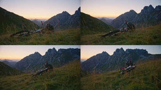 手持拍摄的男子骑自行车坐在草地上对落基山脉日落