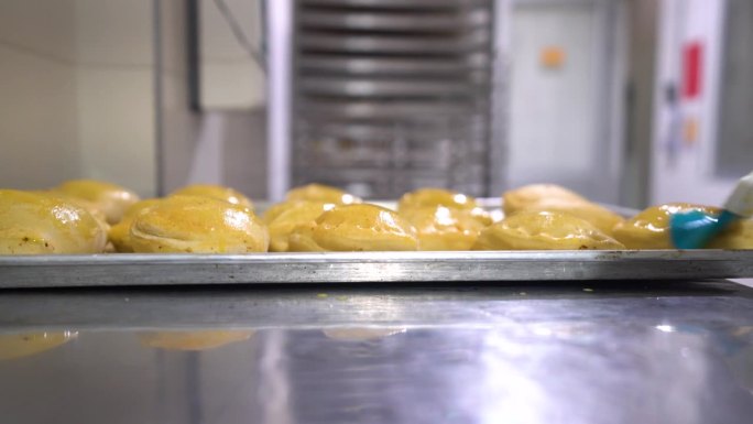 在一家食品加工厂，无法辨认的女员工用蛋液刷肉馅卷饼
