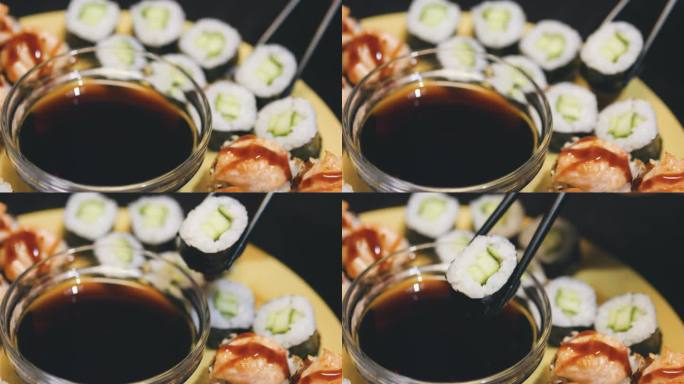 用黑筷子夹起寿司卷，蘸上酱油。