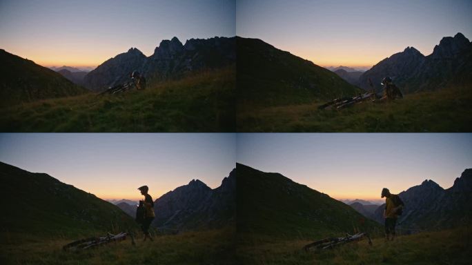 SLO MO手持拍摄的男性山地自行车手背着背包，在黄昏时站在被落基山脉包围的草山上