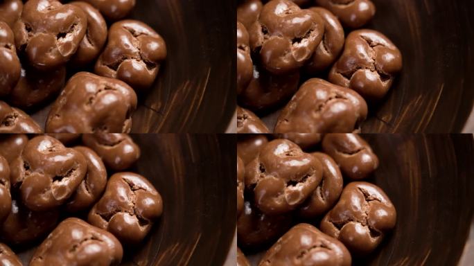 牛奶巧克力釉面核桃在棕色木碗近。旋转