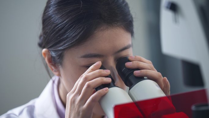 女性科研人员在实验室使用电子显微镜