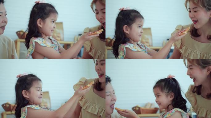 幸福的多代亚洲家庭，6岁的小女孩用草莓酱做面包，早上在家喂给她美丽的妈妈和奶奶。快乐的女孩，妈妈和老