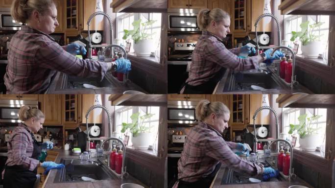 成熟的女人，管理员戴着防护手套在厨房里清洗水龙头和水槽。手持摄像机运动