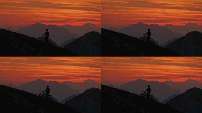 SLO MO剪影男运动员站在山上对戏剧性的橙色天空日落