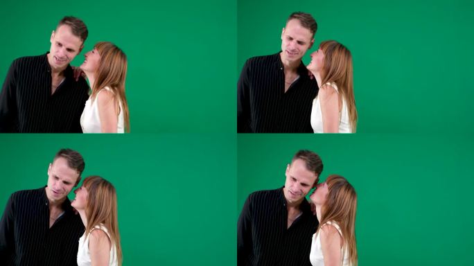 一个男人和一个女人在绿色的背景笑在耳边低语一个秘密笑笑用手指在脸颊上亲吻欧洲夫妇家庭没有秘密八卦情绪