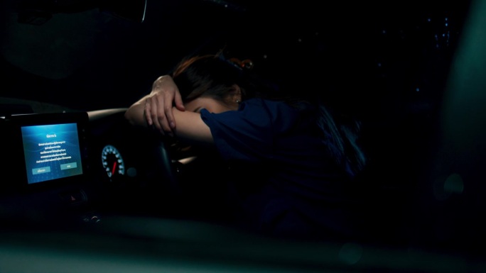 疲惫不堪的年轻亚洲女医生或护士，在漫长而艰难的夜班后，在方向盘上打盹，在车里放松，医疗保健女性工作到