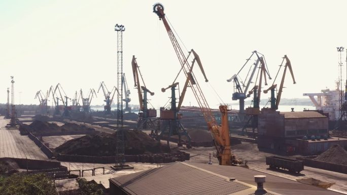 闲置的海港起重机和黑色的煤堆。