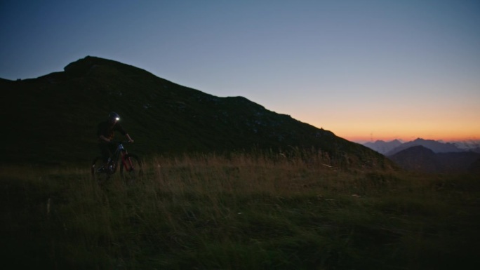 SLO MO坚定的男性骑手骑自行车对山和清澈的蓝天在黄昏
